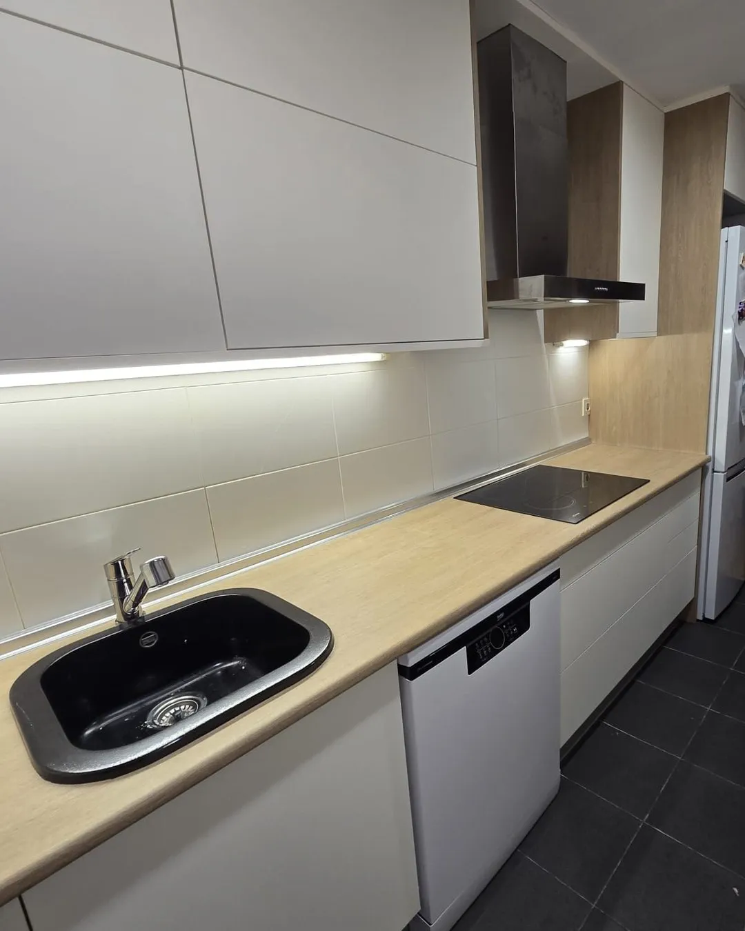 La misma cocina después, con muebles blancos y encimera efecto madera